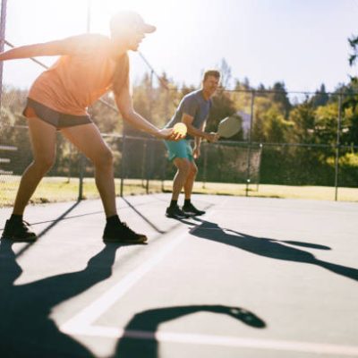 A youthful and fun Caucasian couple in their 50's enjoy the recreational sport of Pickleball on a warm day in the Pacific Northwest.  Shot in Washington state.