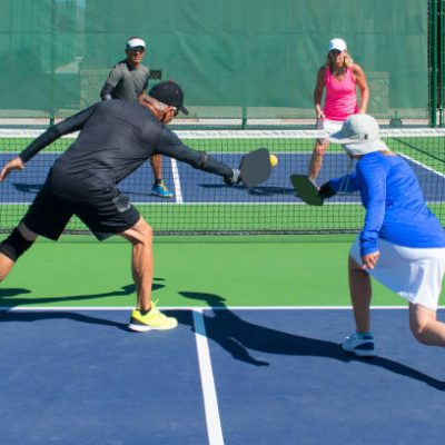 colorful action image of mixed doubles Pickleball teams playing a match